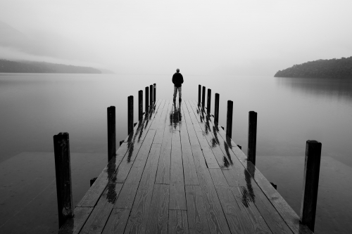 Man standing on wooden pier at Lake Rotoiti in rain; dawn MR available